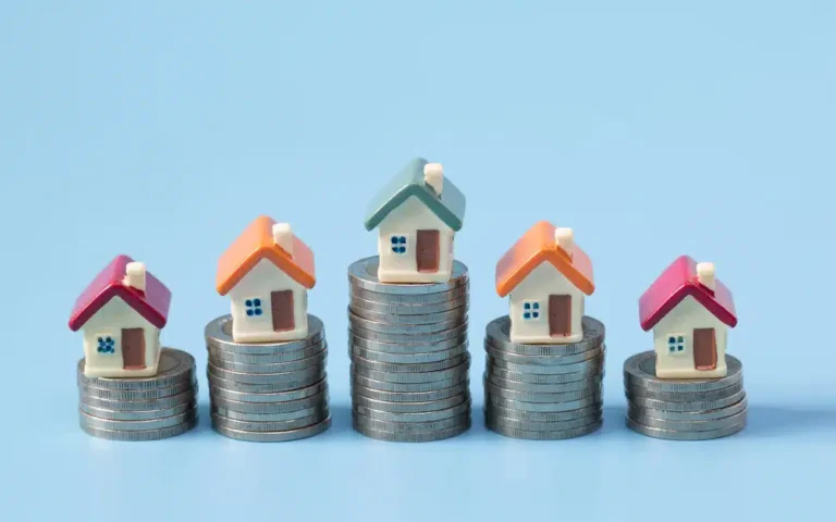 houses stacked on coins to represent wealth building real estate portfolios